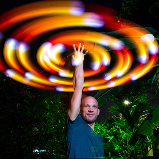 Thomas doing one-handed overhead spiral wraps with flowtoys podpoi